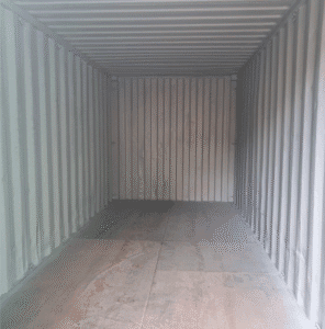Interior of a shipping container with corrugated steel walls and a wooden floor